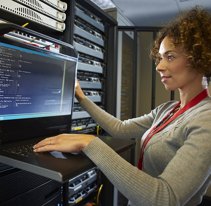 a female IT technician is editing the programme on the network server in a server room