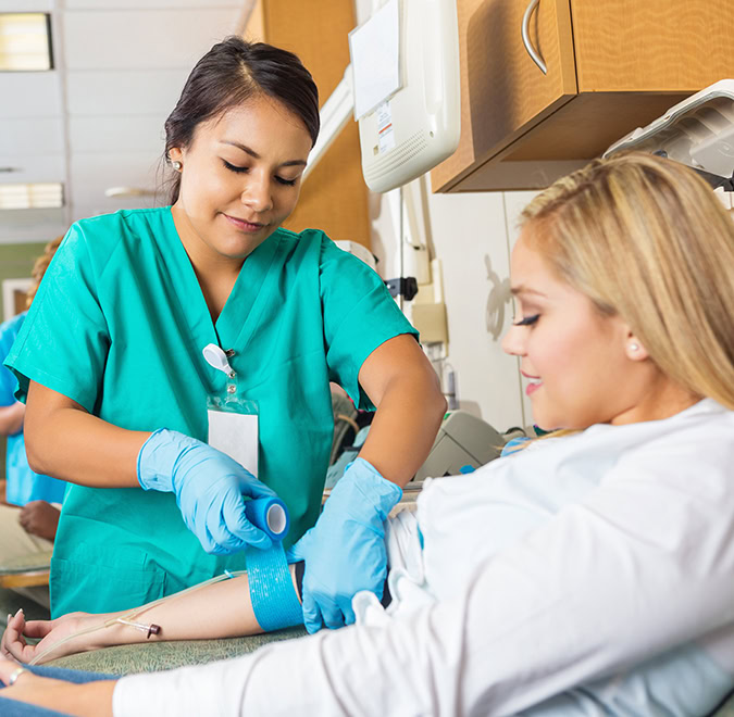 Nurse bandaging arm of patient after she donates blood
