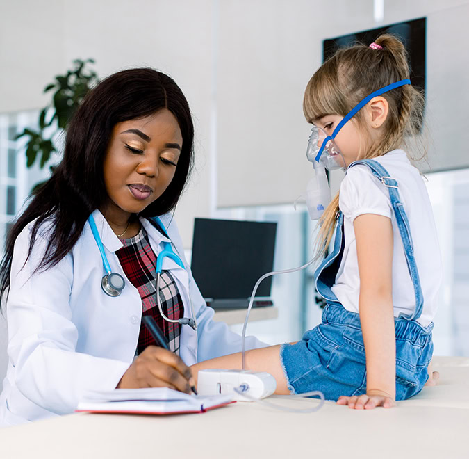 Young African female Doctor helping to little girl with nebulizer mask. Medical doctor applying medicine inhalation treatment on a little girl with asthma inhalation therapy by the mask of inhaler.