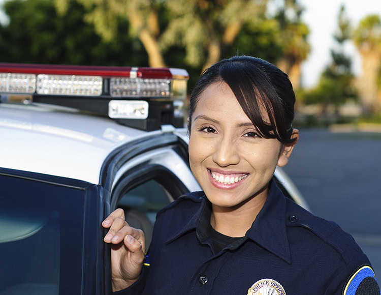 a Hispanic police officer smiling next to her unit