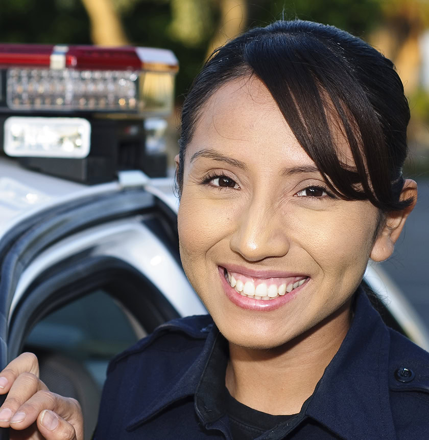 a Hispanic police officer smiling next to her unit