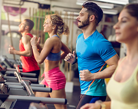 Small group of athletic people exercising in a health club and jogging on running tracks