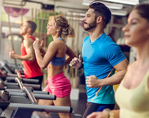 Small group of athletic people exercising in a health club and jogging on running tracks