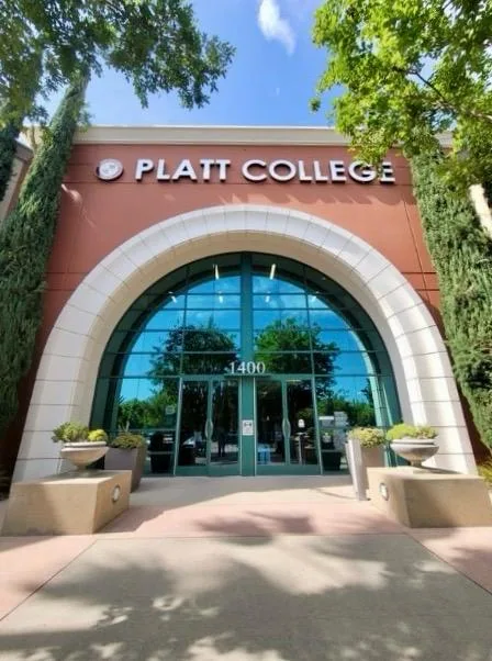 Platt College entrance with glass arch and greenery in Anaheim, California.