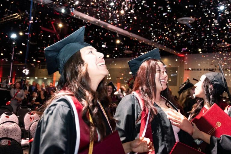 Students celebrating graduation at Platt College with confetti and caps.